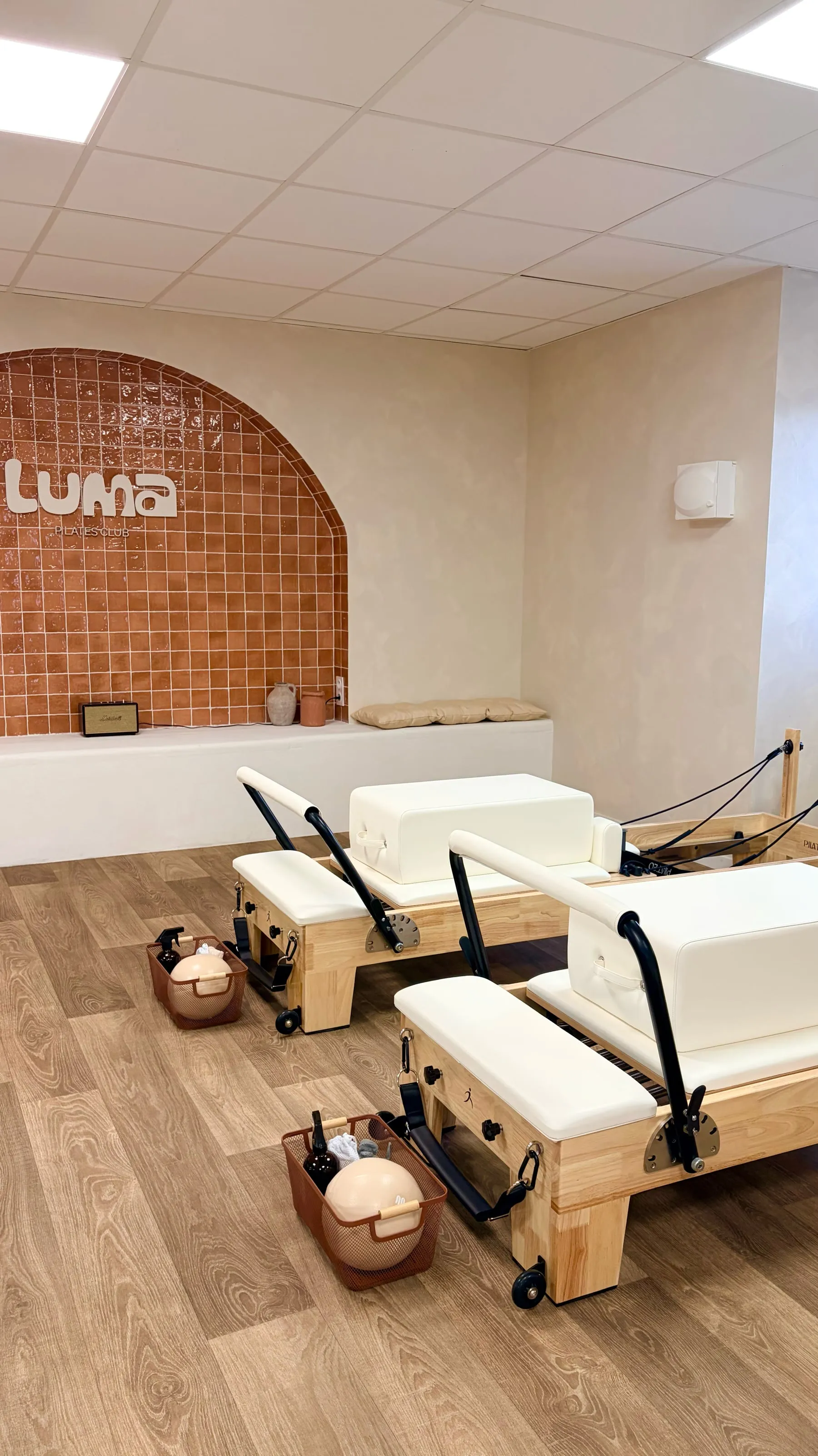 Machines Reformer en bois devant l'arche en zellige terracotta et le logo du studio Luma Pilates Club à Six-Fours-les-Plages